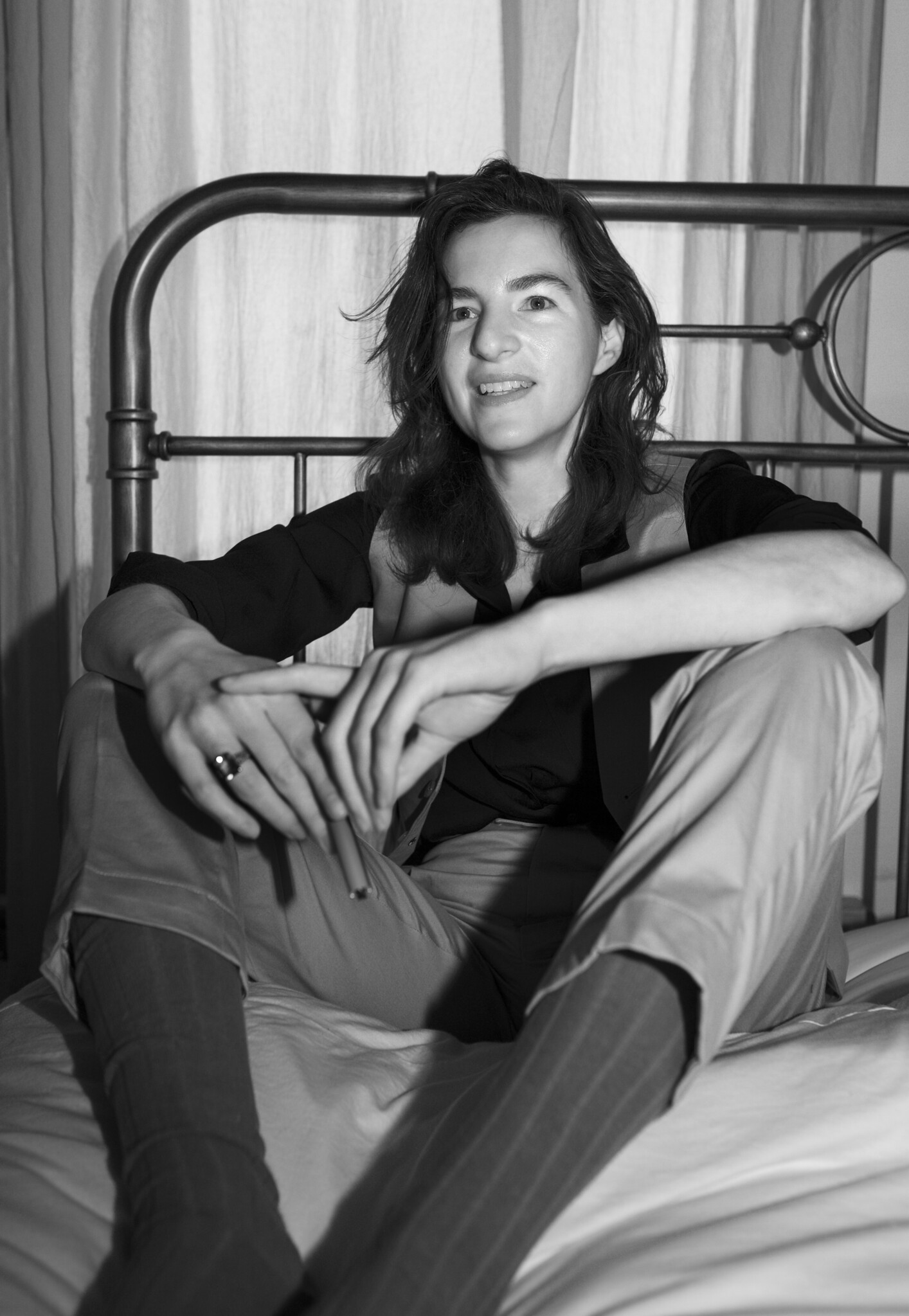 A photo of Maggie Thrash in a suit on a bed holding a pen